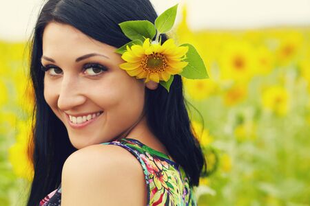 portrait of attractive brunette woman in a field of sunflowersの写真素材