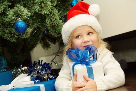 little girl in santa hat holding a giftの写真素材
