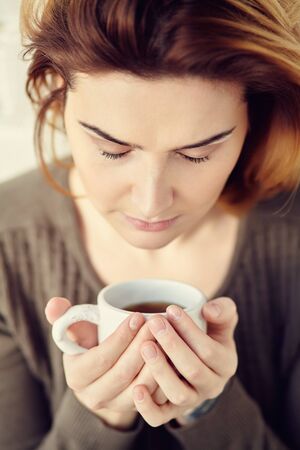 portrait of young attractive smiling woman with a cup of morning coffee or tea.の写真素材