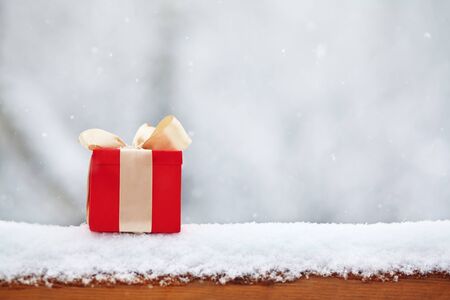 red winter Christmas gift box in snow background outdoors.の写真素材