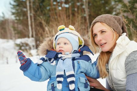 happy mother and baby in winter park. family outdoors. cheerful mommy with her child.の写真素材