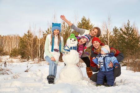 portrait of a cheerful family with snowman. happy children and parents in the winter outdoors.の写真素材