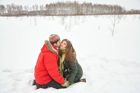Young happy kissing couple in love in the winter outdoors.の写真素材