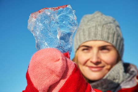 playful woman with a piece of ice in her hands on the winter.の写真素材