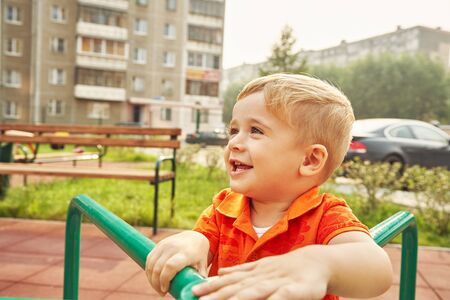 Active little boy on playground. playing child on merry go round.の写真素材