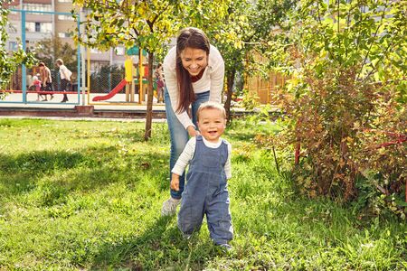 young mother playing with her baby. Mom and son walking in a park.の写真素材