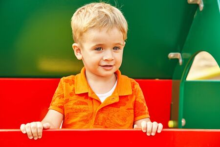 funny little boy on playground. playing child on slide.の写真素材