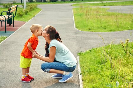 outdoor portrait kissing mother and son. child and mom walking.の写真素材