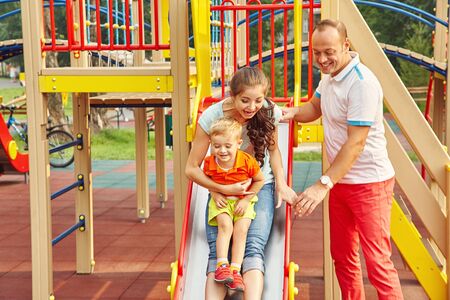 child with parents at a playground. Mom, dad and son. playing family outdoors.の写真素材