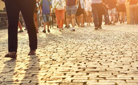 a lot of people walking on a city street. blurred legs and cobbles.の写真素材
