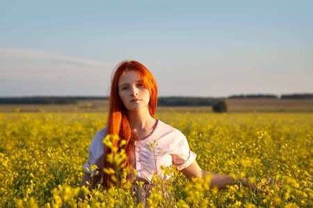 sexy redhead woman outdoors. Beautiful stylish romantic young girl in yellow field.の写真素材