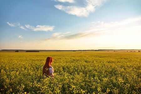 sexy redhead woman outdoors. Beautiful stylish romantic young girl in yellow field.の写真素材
