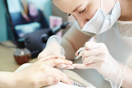 beautician making hardware manicure. woman hands receiving nail procedure in beauty salonの写真素材