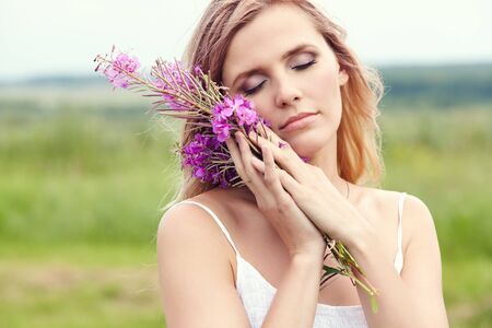 outdoor portrait of a beautiful middle aged blonde woman in a field with flowers.の写真素材