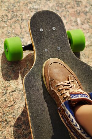 skater with a longboard closeup. trendy casual hipster person a skateboard.