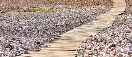 wooden boardwalk on a tropical beach pebble.の写真素材