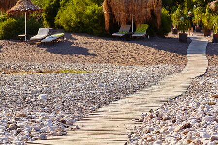 wooden boardwalk on a tropical beach pebble.の写真素材