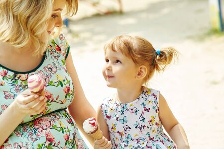 Mom and child eating ice cream. mother and daughter outdoors.の写真素材