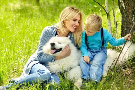 outdoor portrait mother, son and dog. child and mom walking samoyed laika.の写真素材