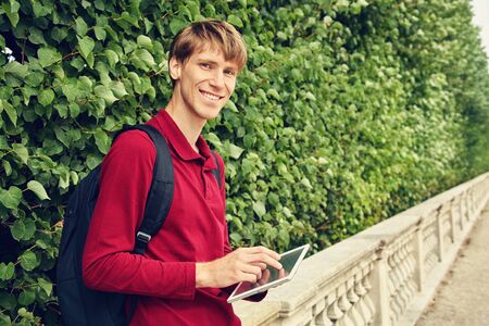 handsome young man using tablet computer. student with a backpack.の写真素材