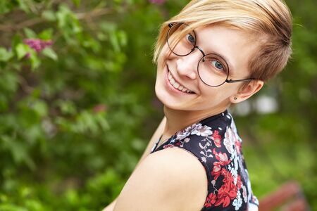 portrait of a beautiful smiling young woman in glasses in a park.の写真素材