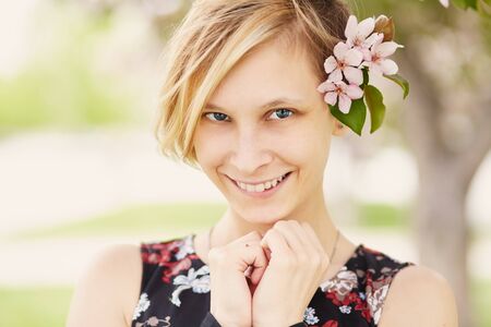 Beautiful smiling young woman with spring flowers in her hair.の写真素材