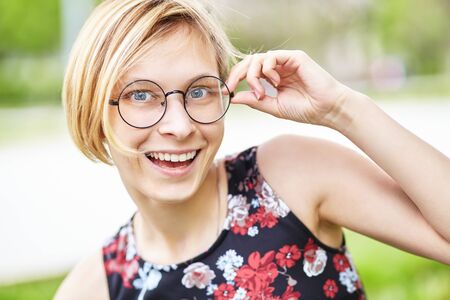 portrait of a beautiful smiling young woman in glasses in a park.の写真素材