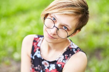 portrait of a beautiful smiling young woman in glasses in a park.の写真素材