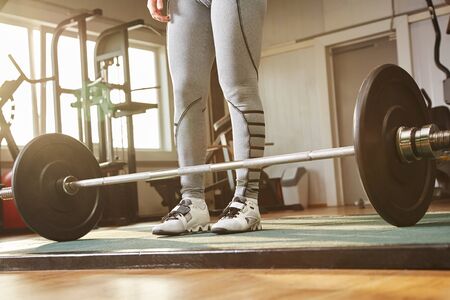 closeup legs of a sports woman training with a barbell in a gym.