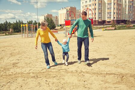 happy playing family outdoors. young parents with a baby walking in the summer. Mom, dad and child.の写真素材