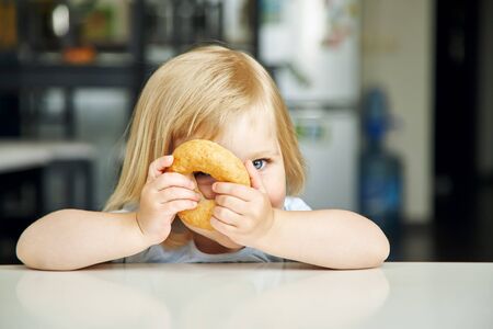 portrait of a funny little girl with bagel. child playing at home.の写真素材
