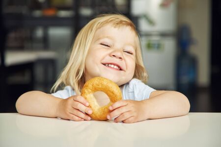 portrait of a funny little girl with bagel. child playing at home.の写真素材