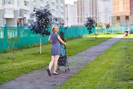 young mother walking with a baby sitting in a stroller. mom and little daughter.の写真素材