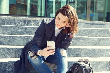 outdoor portrait of a stylish woman with smartphone.の写真素材