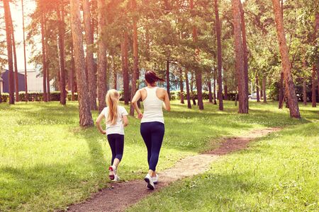 running sporty mother and daughter. woman and child jogging in a park. outdoor sports and fitness familyの写真素材