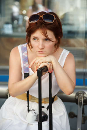 female traveler with a suitcase awaiting a train at railway station.の写真素材