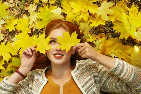 woman with yellow maple leaves in autumnの写真素材