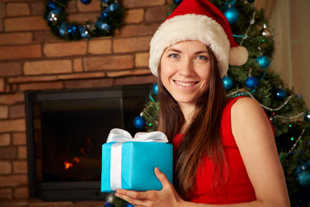 woman in santa hat with gift box near Christmas tree.の写真素材