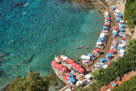 sea beach with people on vacation in sun loungers and sun umbrellas near the water.の写真素材