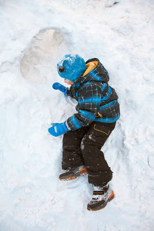 funny little boy playing in snow houseの写真素材