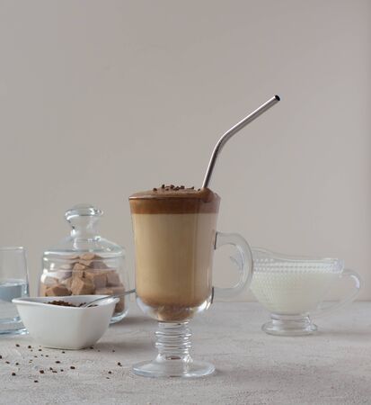 The recipe for the popular coffee dalgon coffee drink in a glass cup with a metal straw. Milk coffee sugar water. Side view.の写真素材