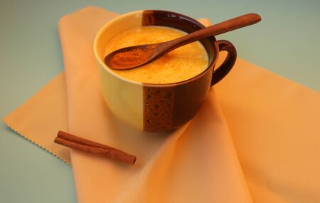 Golden coconut milk with turmeric and cinnamon on a blue background in a tan cupの写真素材