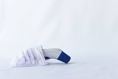 Electronic thermometer, protective medical mask, side view, copyspace. Digital medical infrared frontal non-contact for measuring temperature.の写真素材