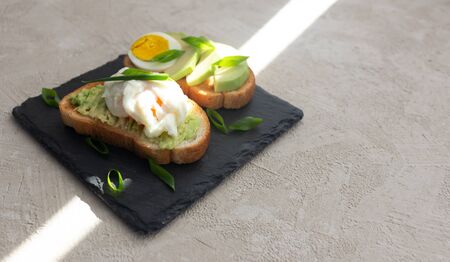 Sandwich fried with avocado and egg onions on a black stand.の写真素材