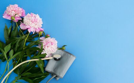 Medical Worker Day greeting card with place for text. The concept of gratitude to the doctors. Peonies stethoscope and tonometer on a blue background.の写真素材