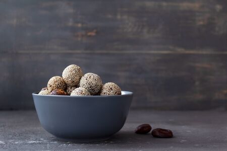 Homemade energy balls in a bowl on a gray background with place for text. Healthy snack. Proper nutrition from dates and nuts.の写真素材