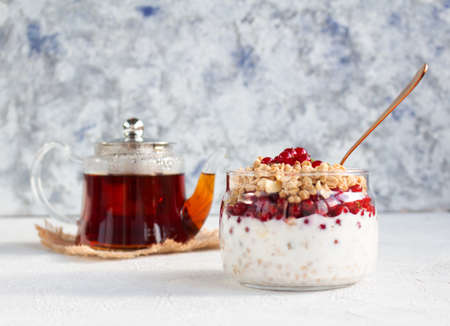 Breakfast is beautiful with granola and red currants with yogurt in a glass jar and tea from the...