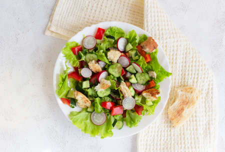 Flat lay. Fattoush salad with tomato, cucumber, radish and toasted pita bread, oil spilled in a white plate on a napkin.の写真素材