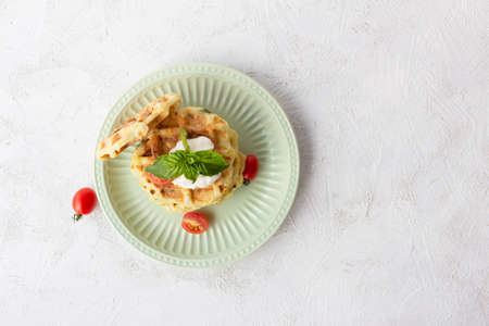 Zucchini waffles on a green plate with sour cream, basil and tomatoes.の写真素材