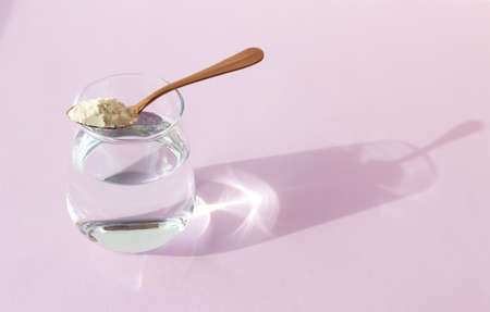 Collagen powder and a glass of water on a lilac background.の写真素材